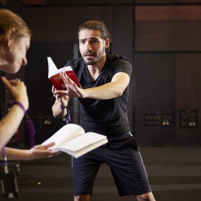 A man holds a text infront of him, his arm is out